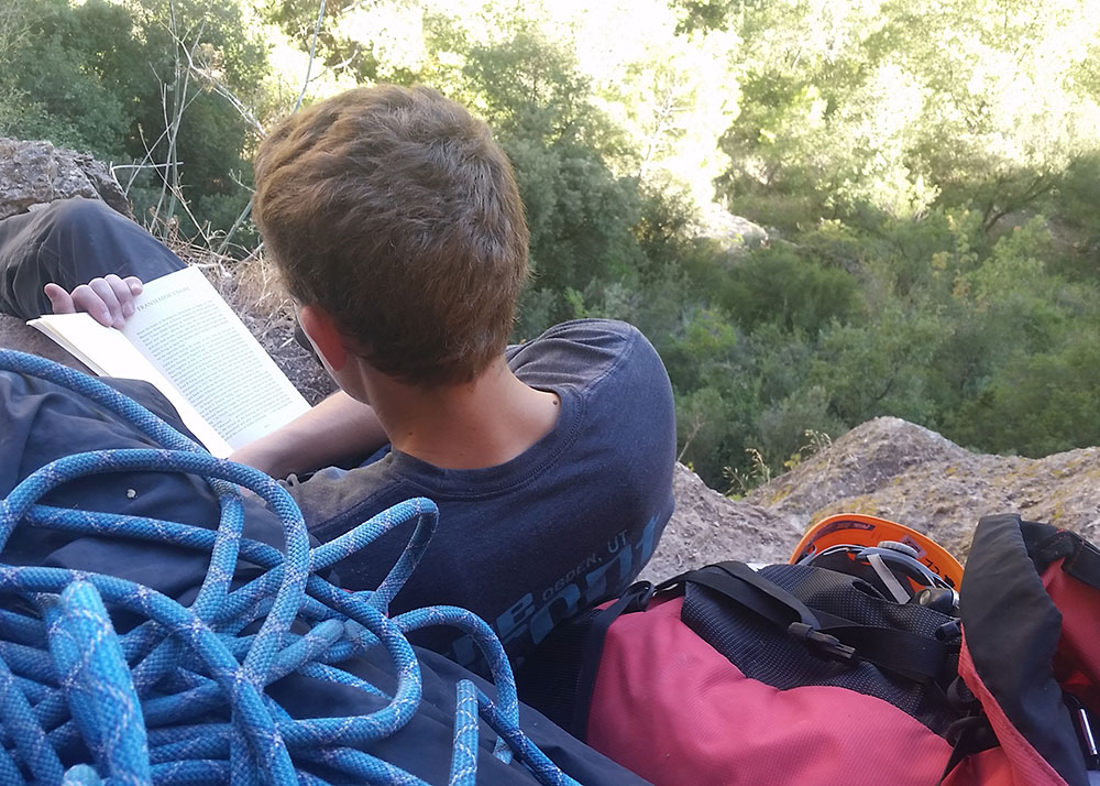 Male climbing student reading