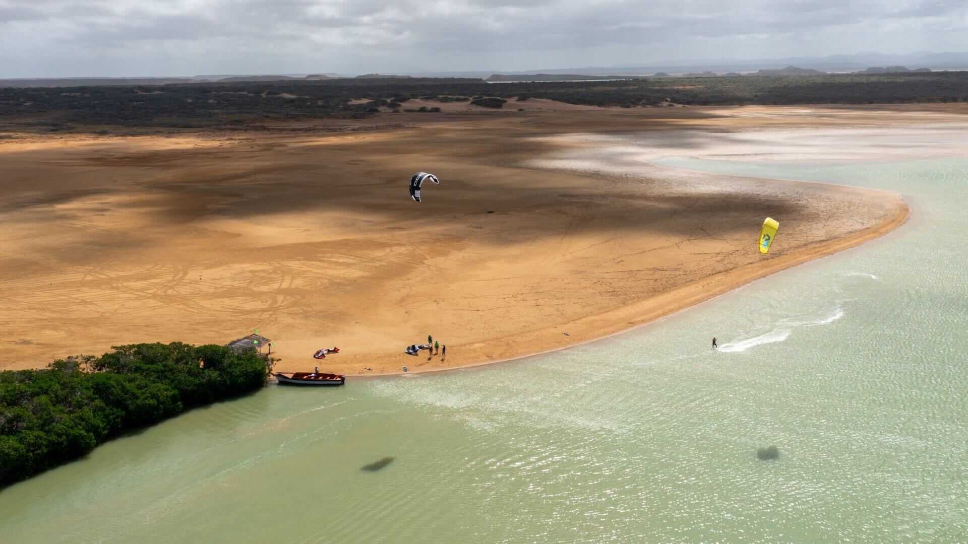 Aerial view of kiteboarders on a turquoise lagoon and sandbar in Colombia
