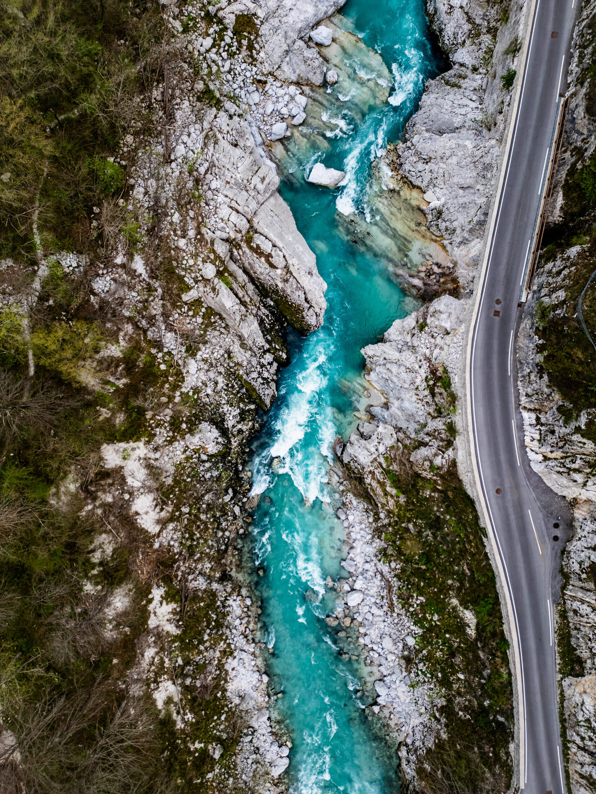 Aerial view of a turquoise alpine river winding through a rocky canyon in the European Alps