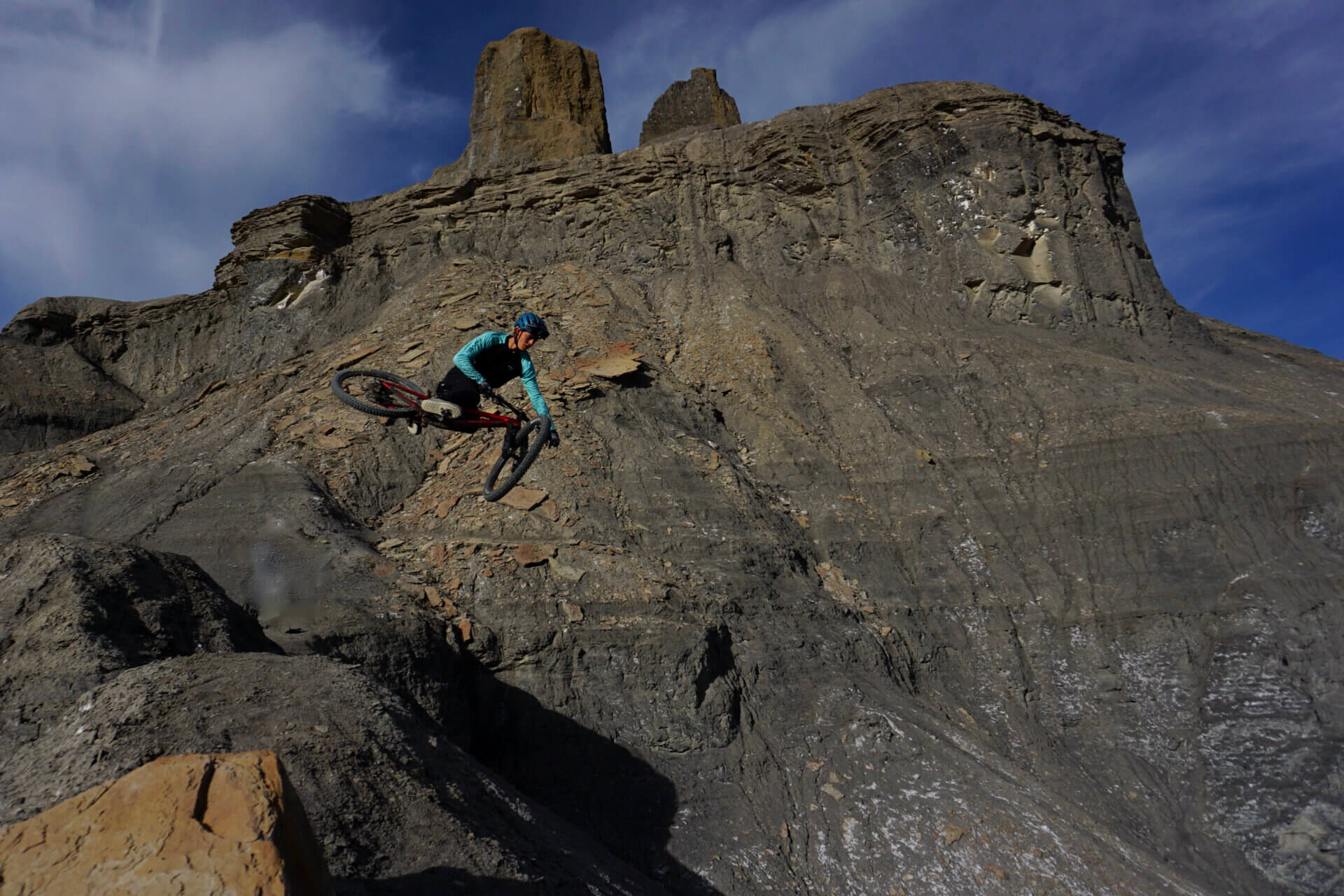 A mountain bike academy student doing a big jump. Mountains in the background.