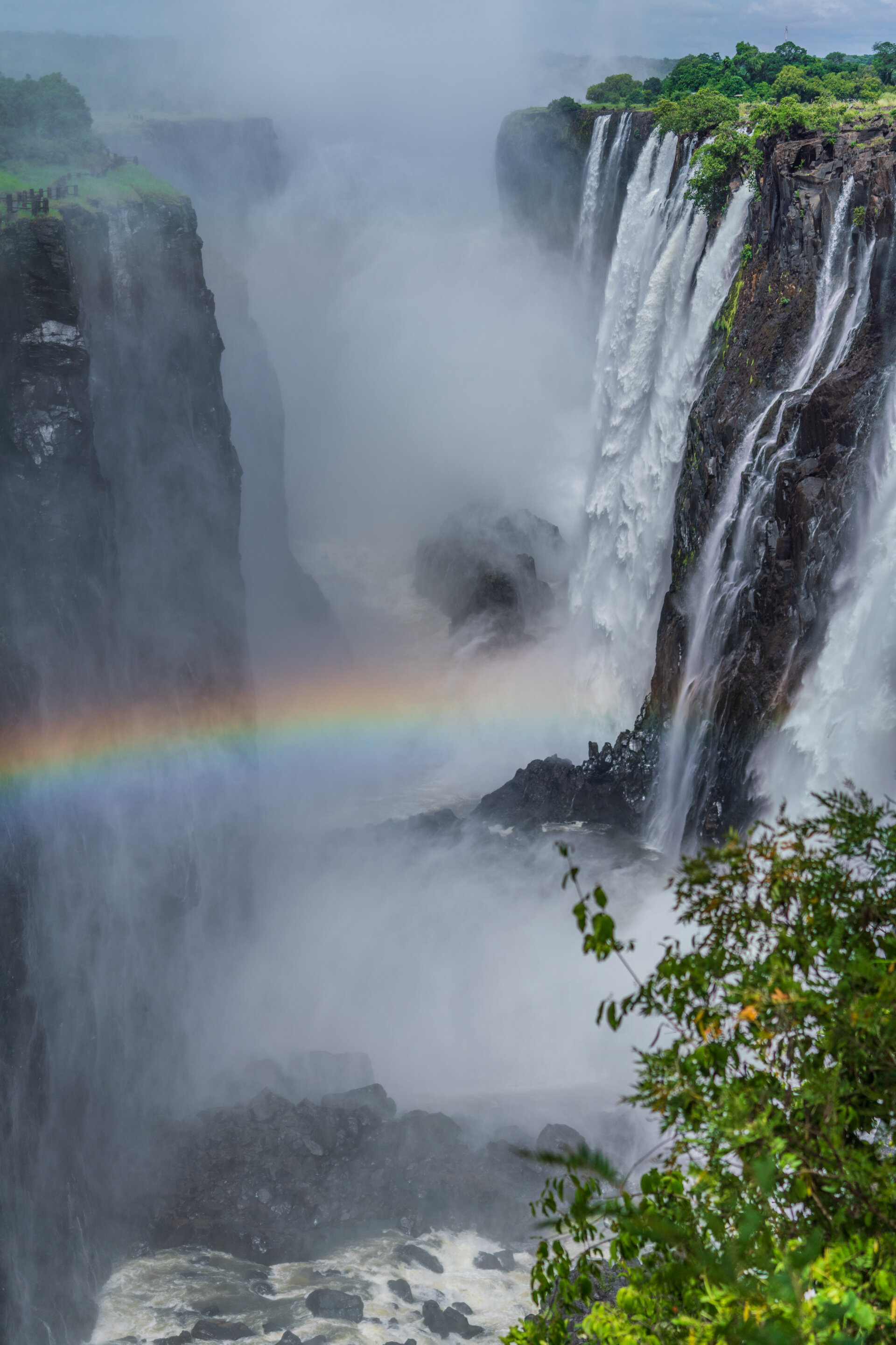 Majestic waterfall with rainbow in misty gorge