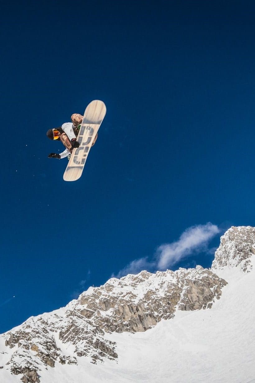Snowboarder grabbing high against a deep blue sky