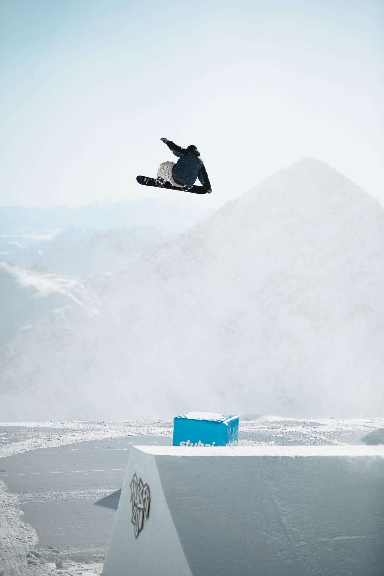 Snowboarder flying off a kicker into a hazy mountain view
