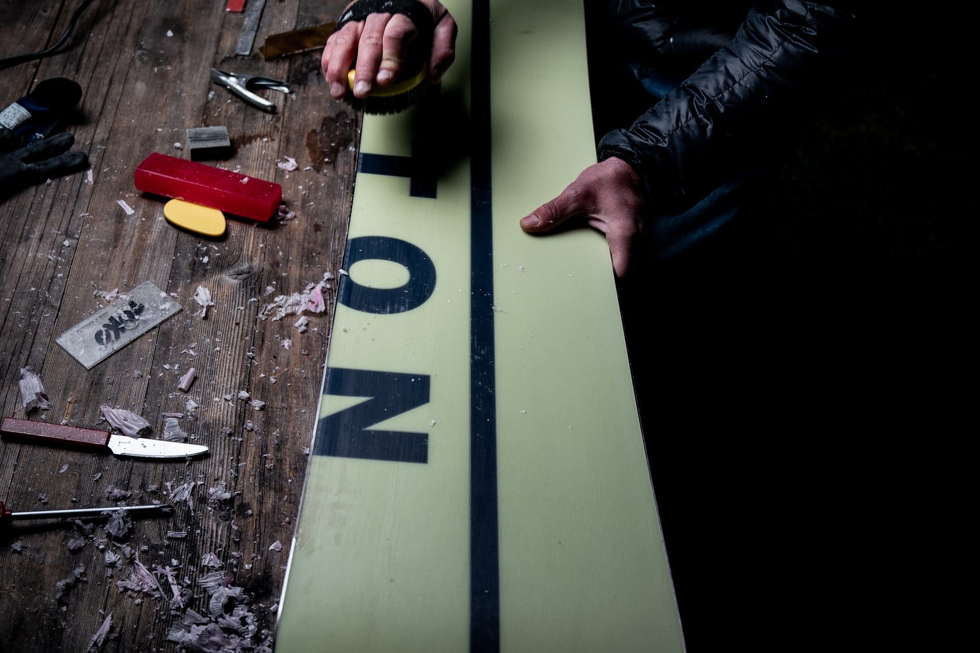 Student waxing and tuning a snowboard at a workbench