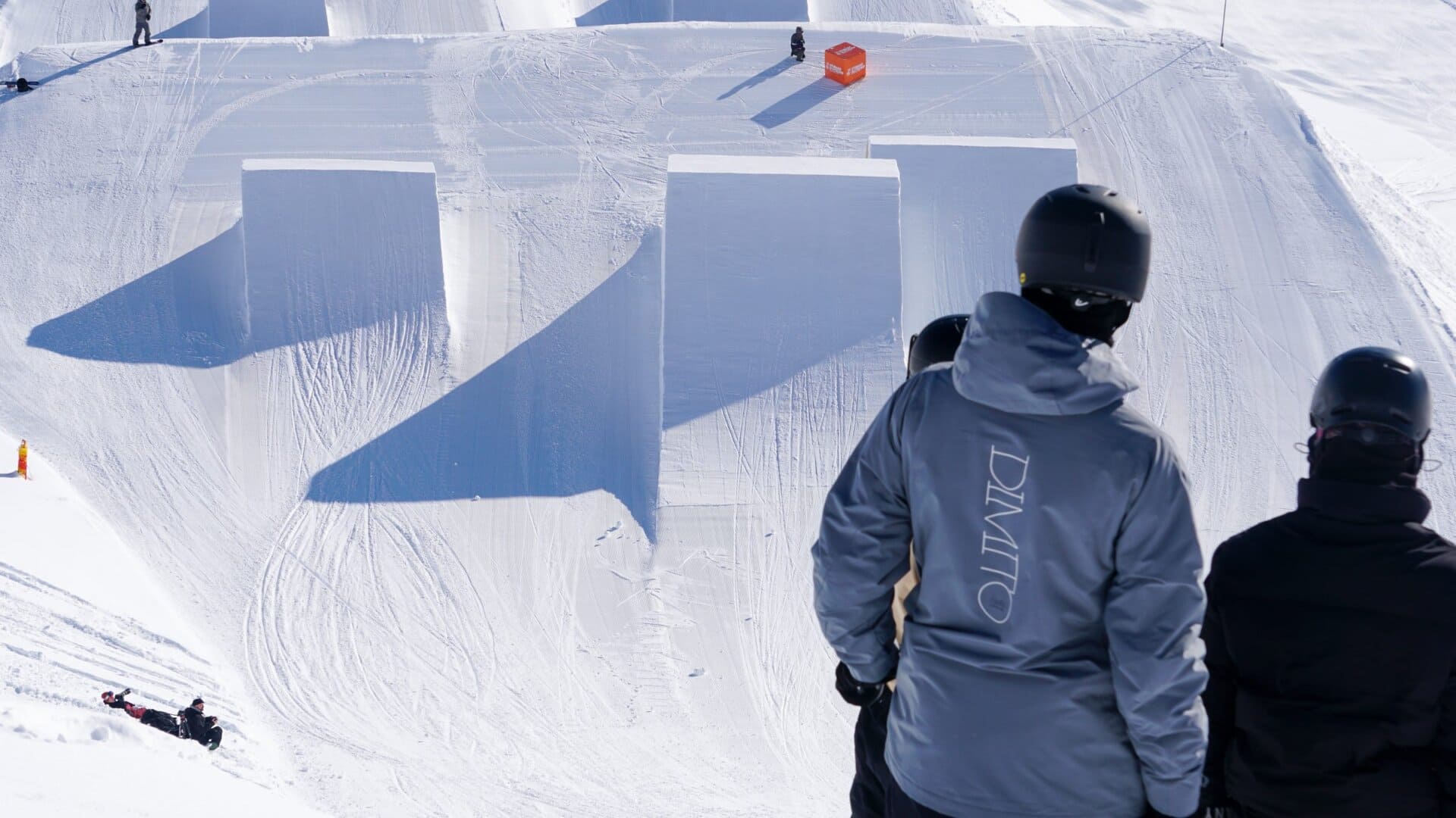 Coaches watching riders on a terrain park jump line