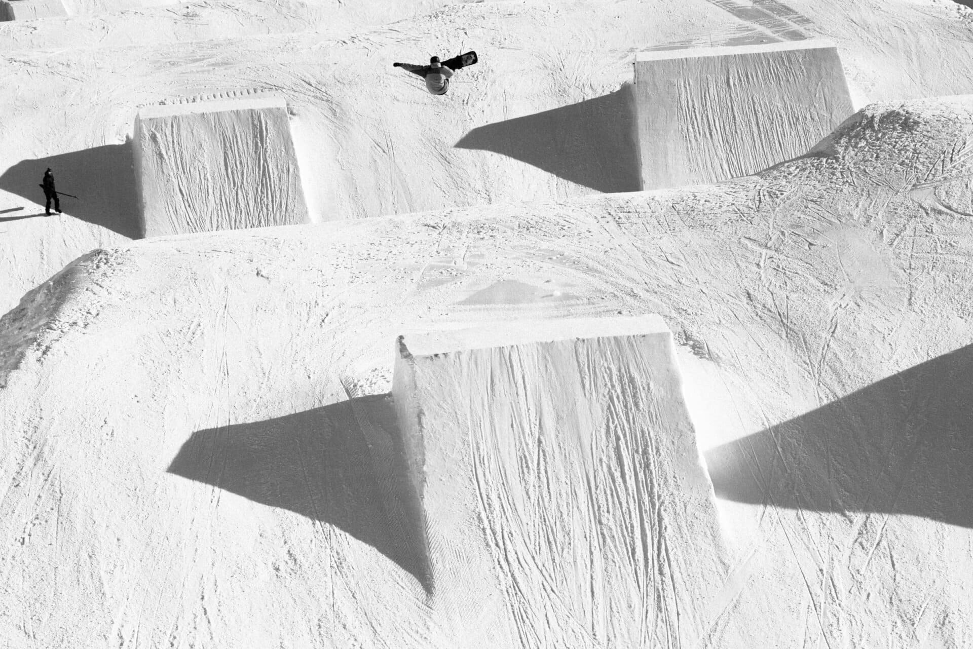 Aerial view of a snowboarder over a line of park jumps