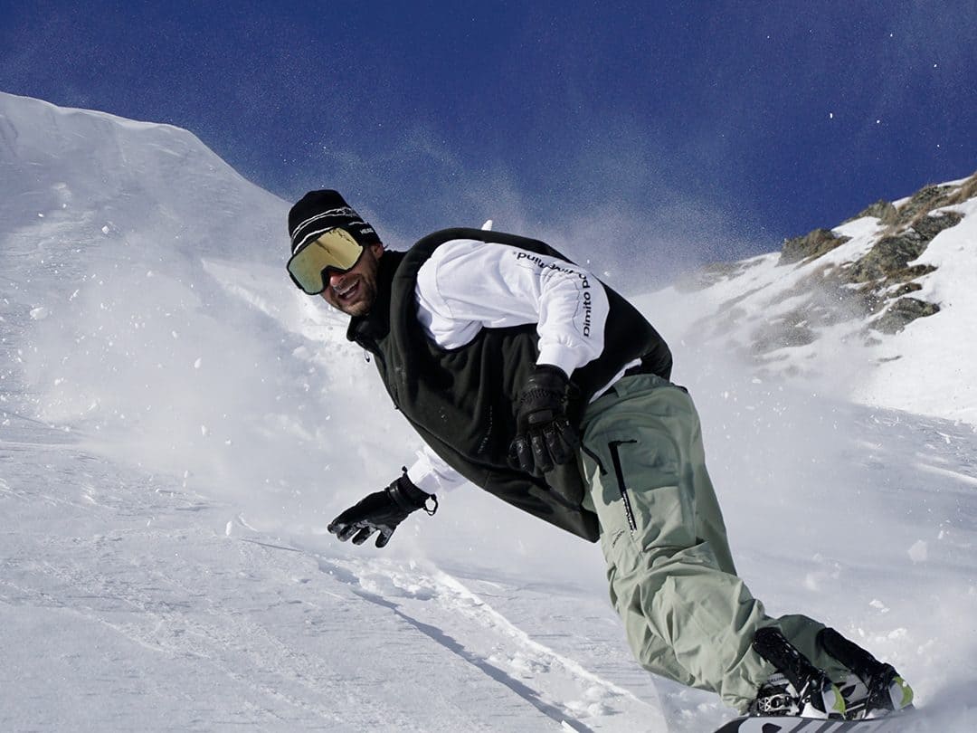 Snowboarder laying down a deep carve on a groomed slope