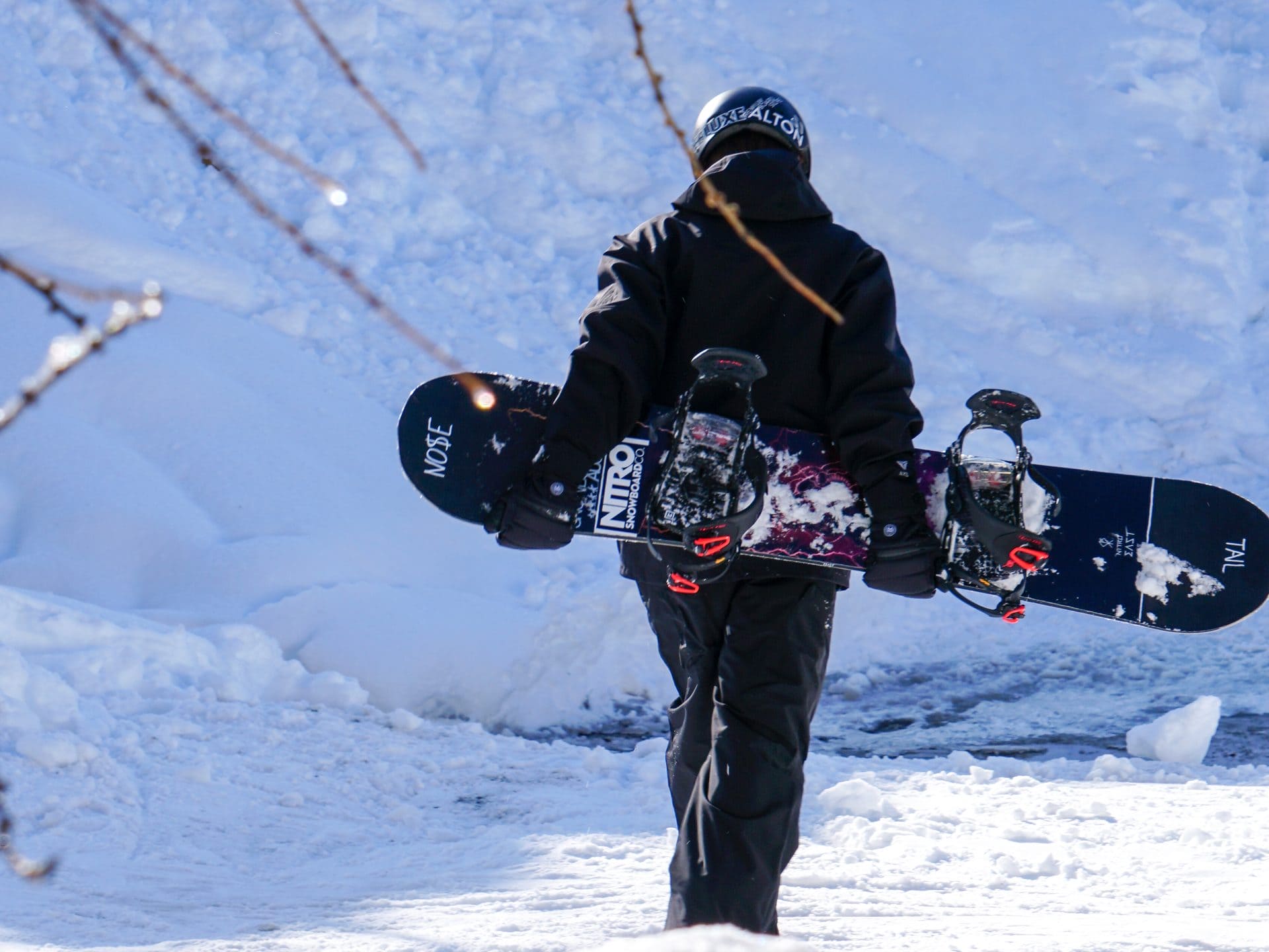 Snowboarder hiking through fresh snow carrying a board on a backpack
