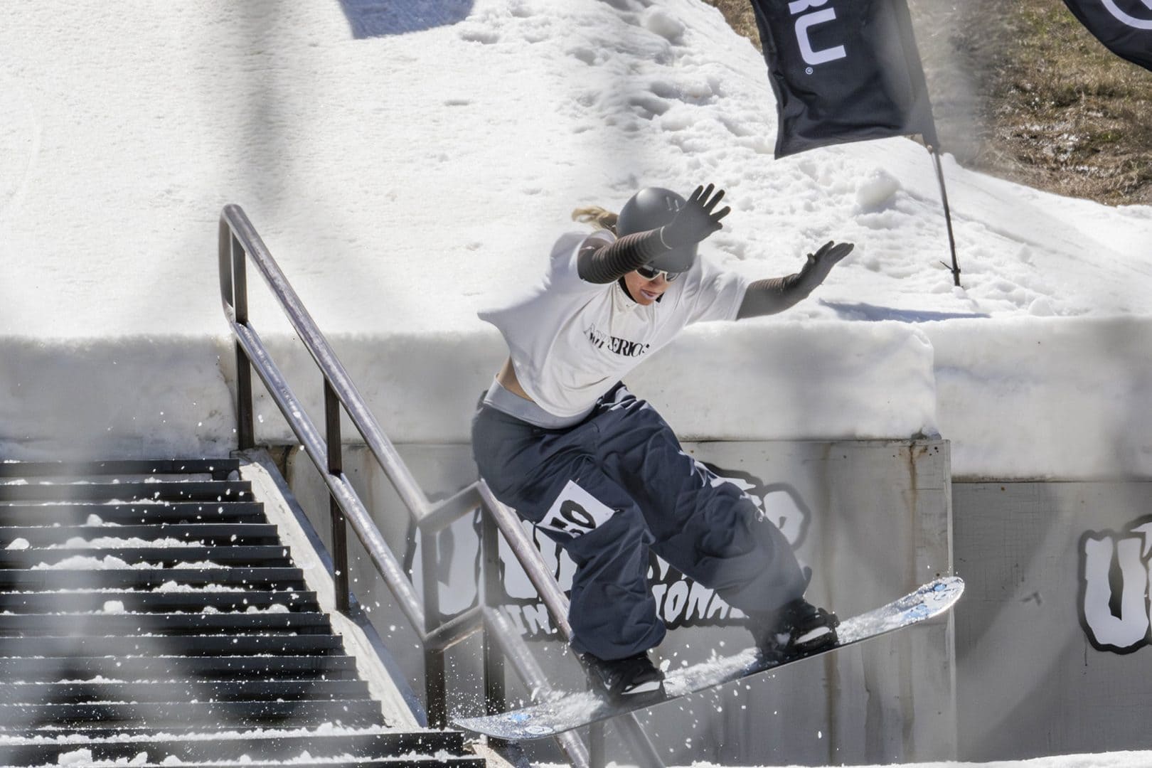 Snowboarder Selin Lakatha sliding a handrail down a snowy staircase in the terrain park